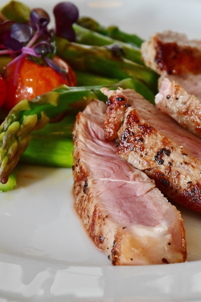 Куски аппетитного мяса на тарелке со спаржей