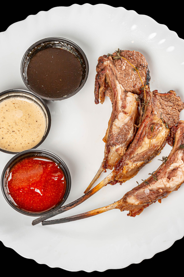 Свиные ребра с соусом на белой тарелке 