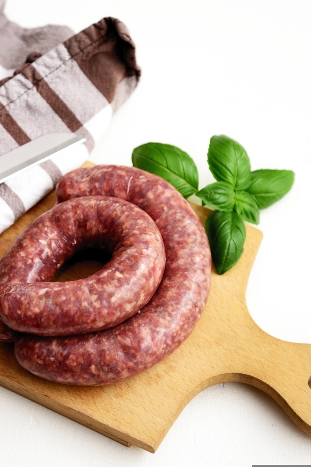 Сырая колбаса на доске с ножом