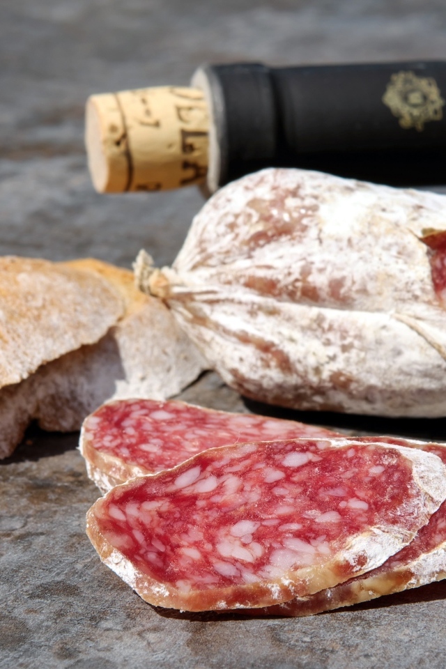 Колбаса салями с хлебом и вином на столе 