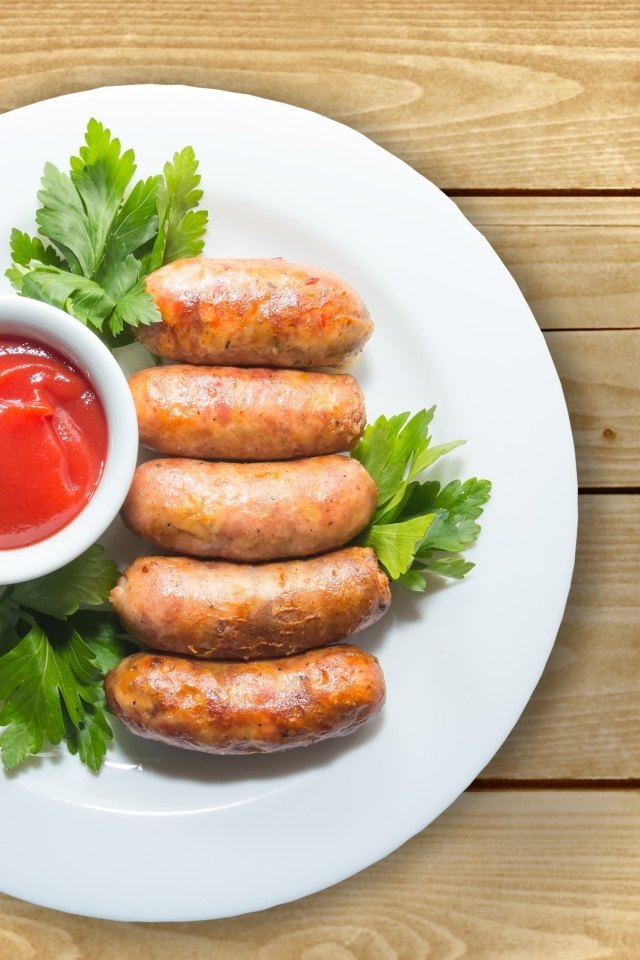 Сардельки на тарелке с соусом и петрушкой