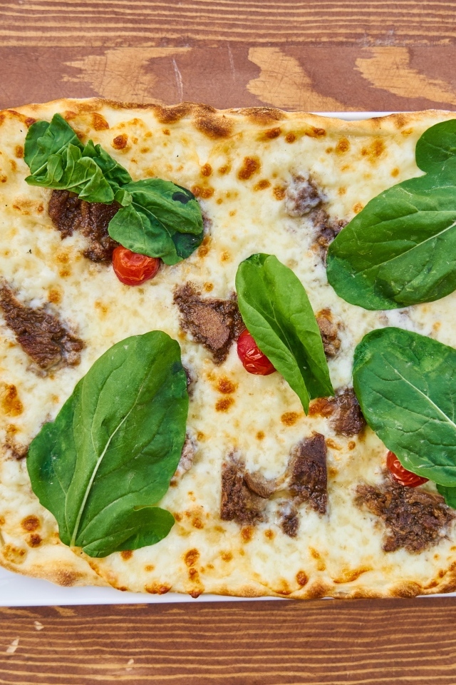 Мясная пицца с сыром и зелеными листьями