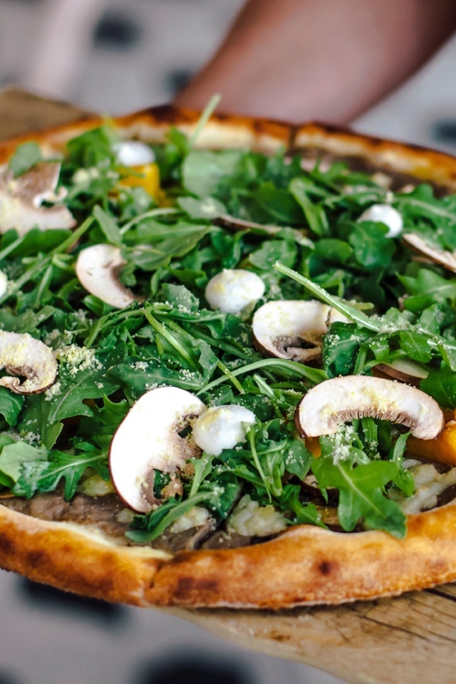Пицца с грибами и листьями рукколы