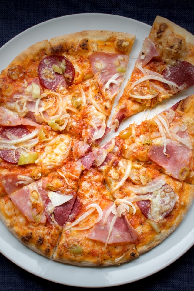 Нарезанная пицца на белой тарелке