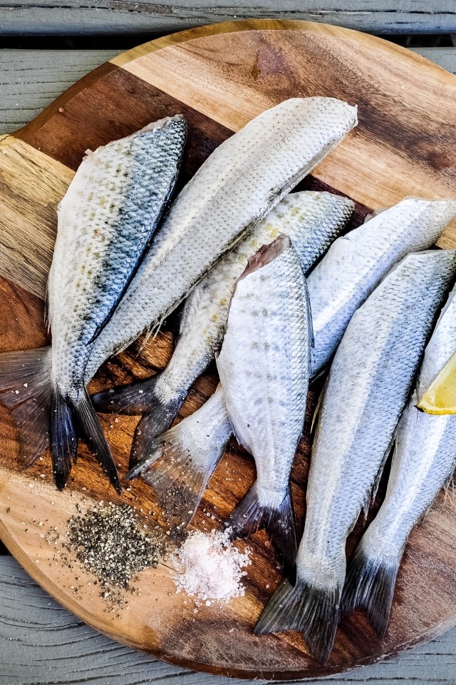 Свежая рыба на доске  с кусочками лимона