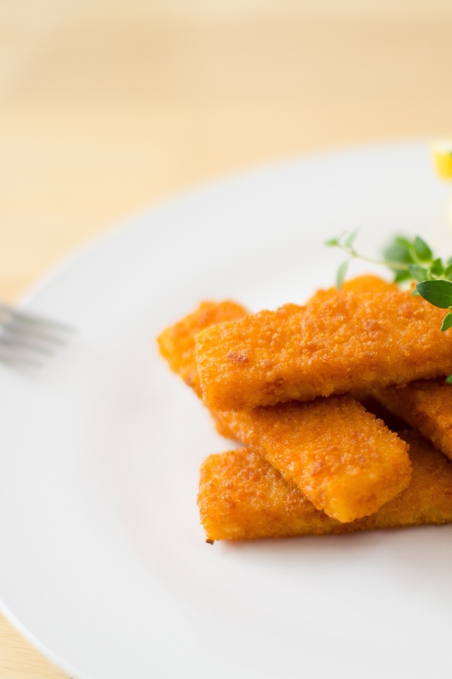 Жареные рыбные палочки на тарелке с лимоном