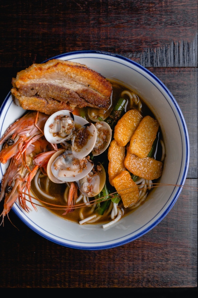 Суп с лапшой и морепродуктами на деревянном столе