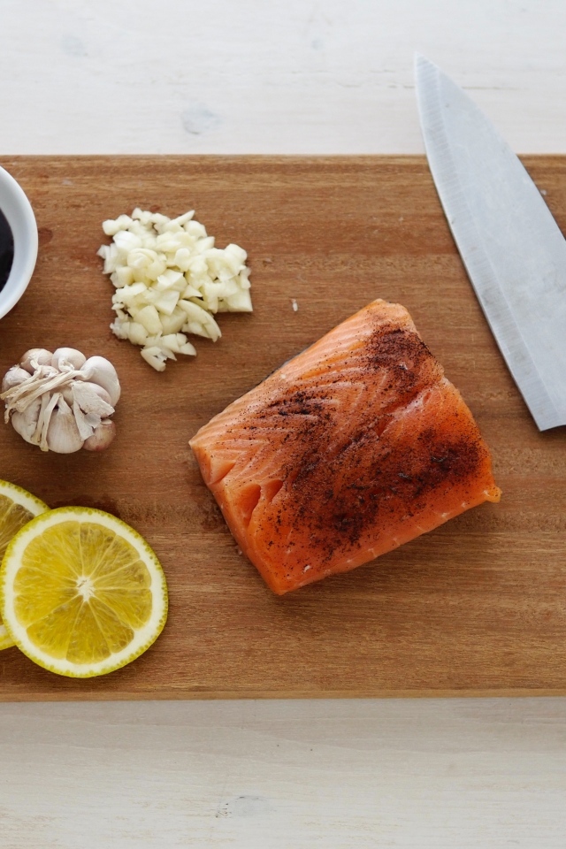 Кусок красной рыбы на доске с лимоном и чесноком