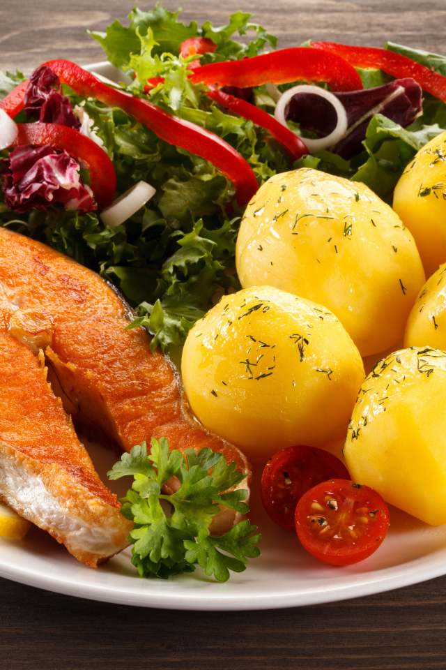 Картофель с кусочками рыбы и зеленью на тарелке