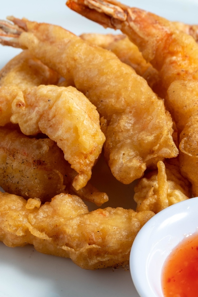 Креветки в кляре на тарелке с салатом и соусом