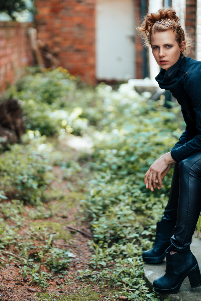 Девушка в черном наряде сидит на окне