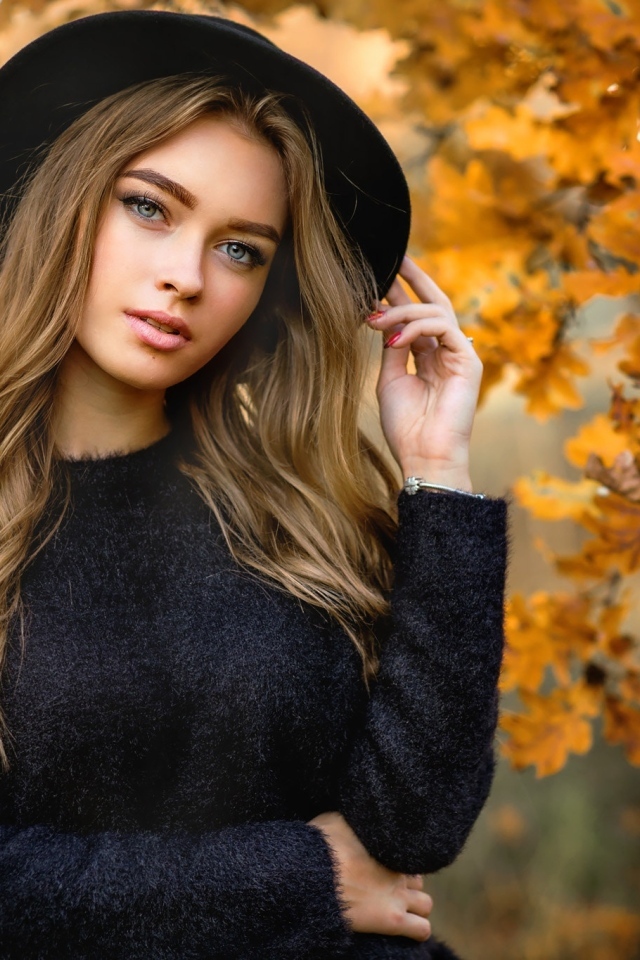 Девушка в черной шляпе стоит у дуба