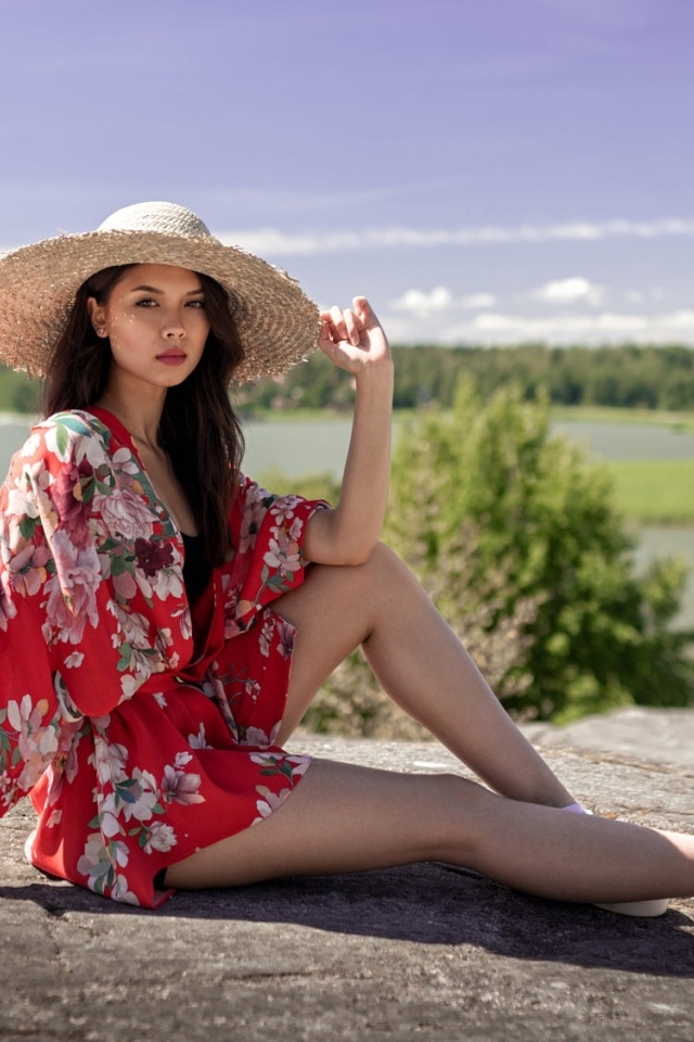 Девушка азиатка в шляпе лежит на камне