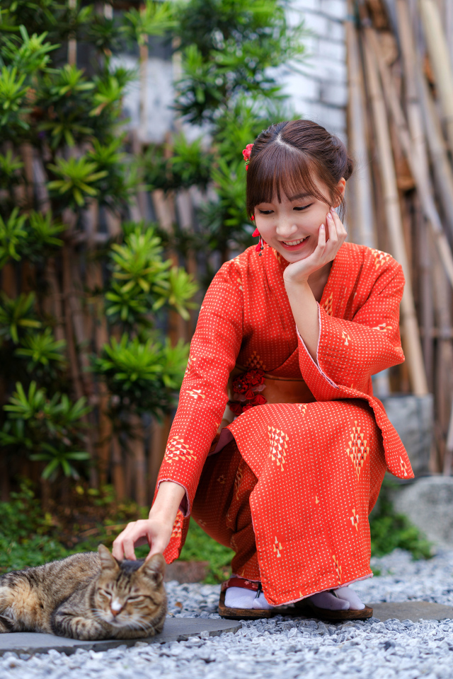 Девушка азиатка в красном платье гладит кота