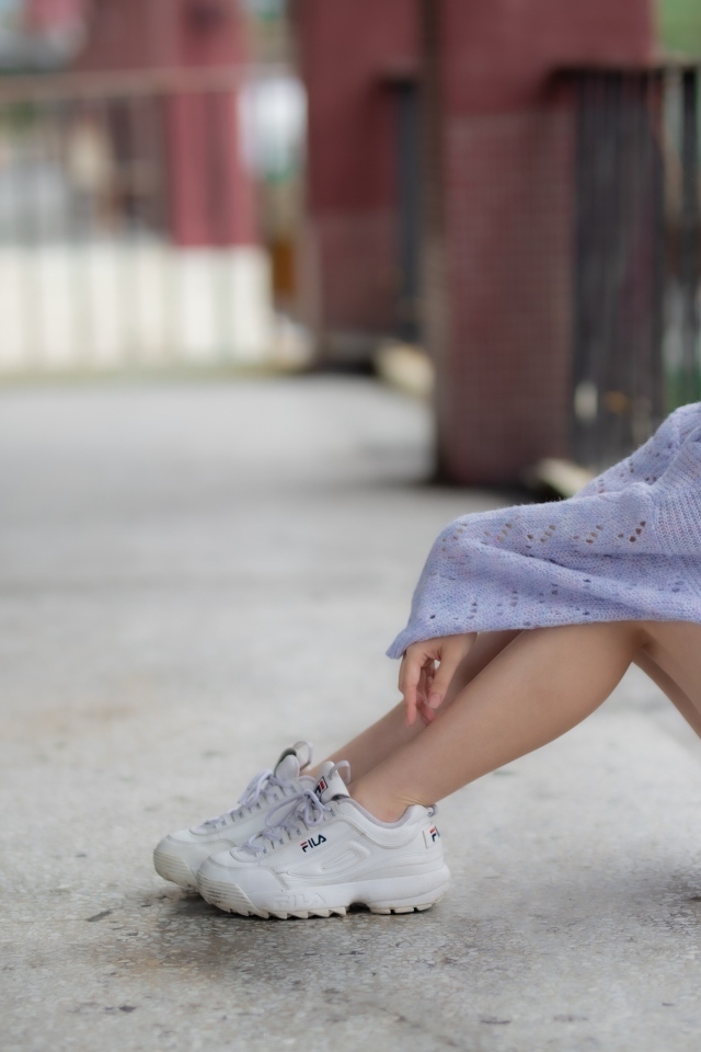 Девушка азиатка в свитере и белых кроссовках 