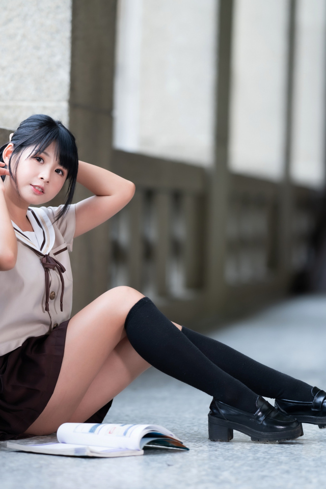 Девушка азиатка в школьной форме сидит на полу