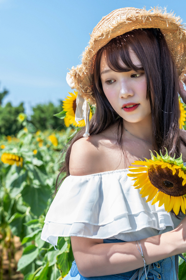 Девушка азиатка на поле с подсолнухами