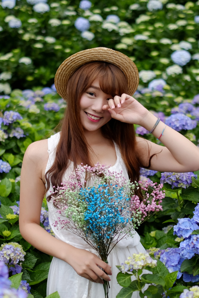 Девушка азиатка у куста с цветами гортензии