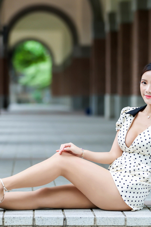 Девушка азиатка сидит в платье на плитке