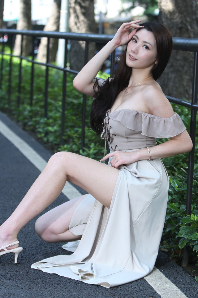 Девушка азиатка сидит у забора