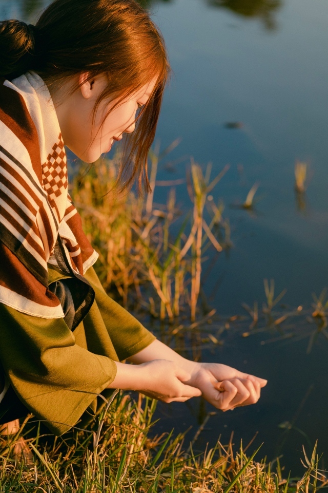 Девушка азиатка сидит у пруда