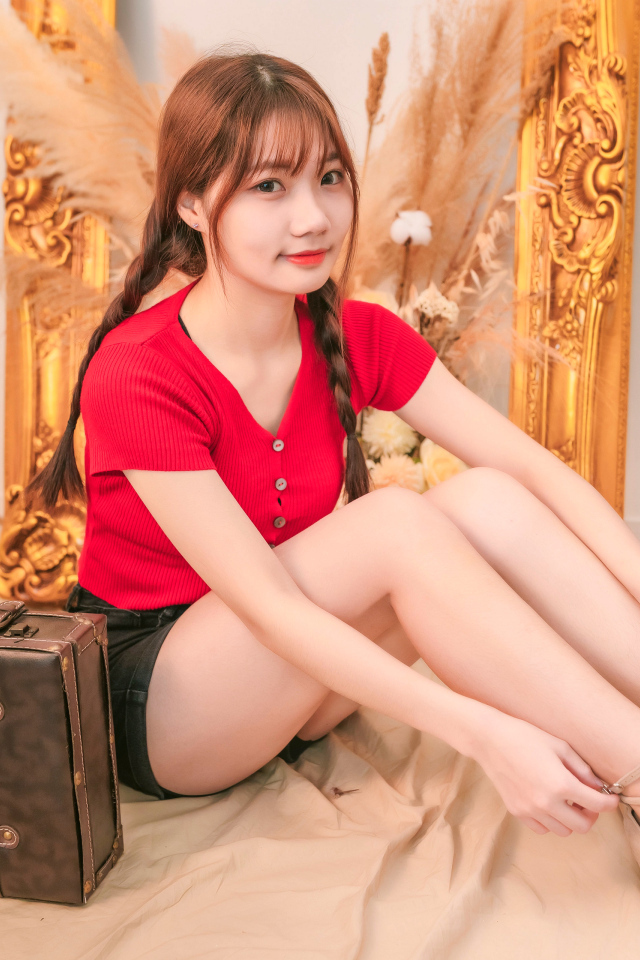 Девушка азиатка сидит на полу с чемоданом