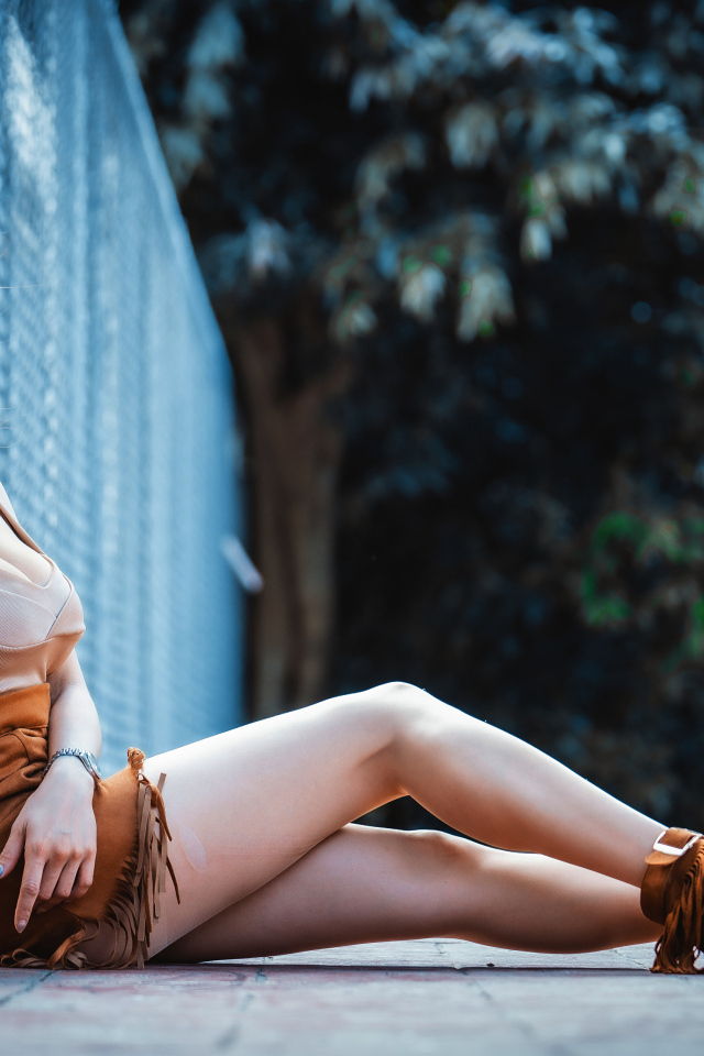 Девушка азиатка сидит на земле у сетки