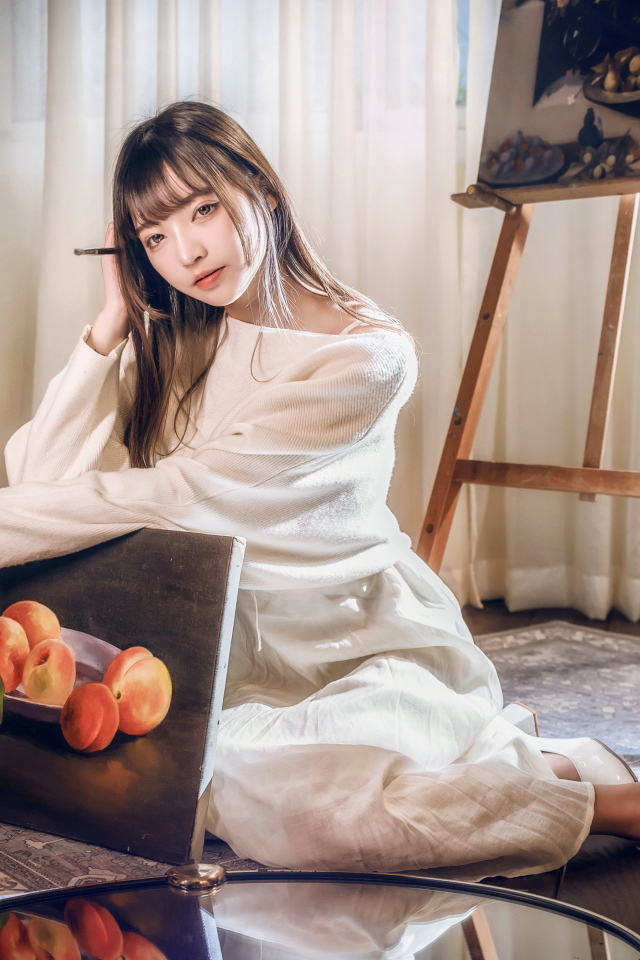 Девушка азиатка сидит с картиной на полу