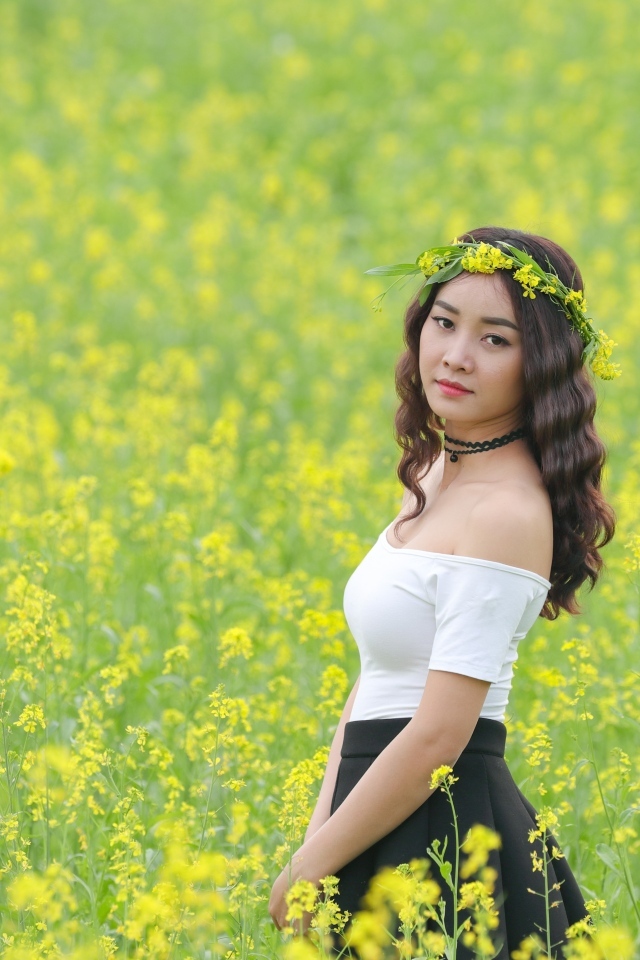 Девушка азиатка стоит на рапсовом поле