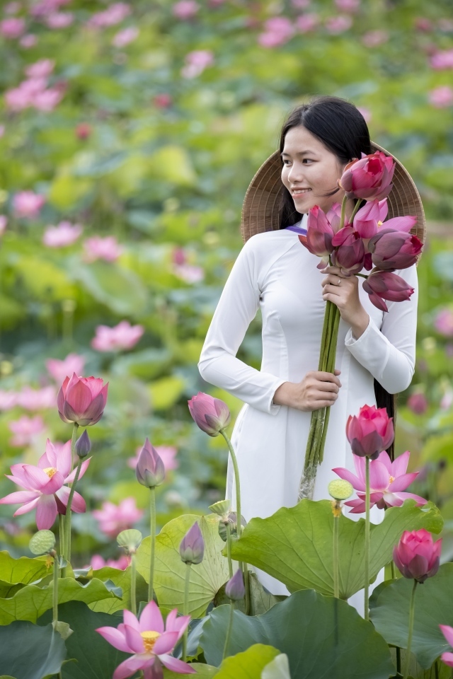 Девушка азиатка с розовыми цветами лотоса в руках