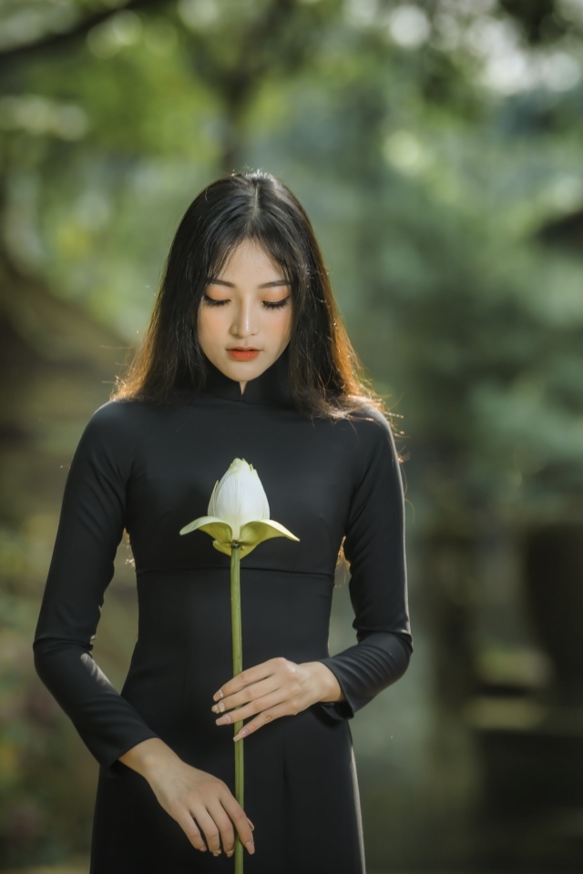 Красивая девушка азиатка в черном платье с цветком лотоса