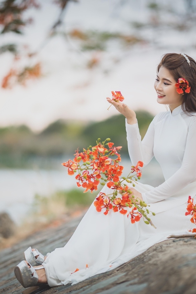 Красивая девушка азиатка в белом платье с цветами в руке