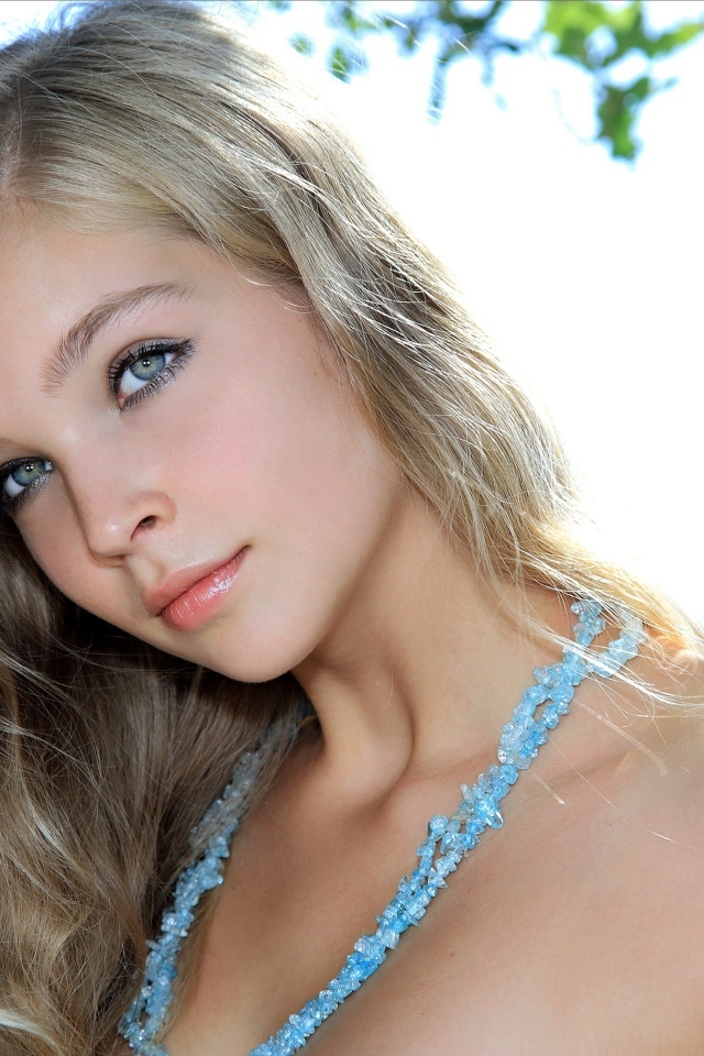 Красивая голубоглазая девушка с бусами на шее