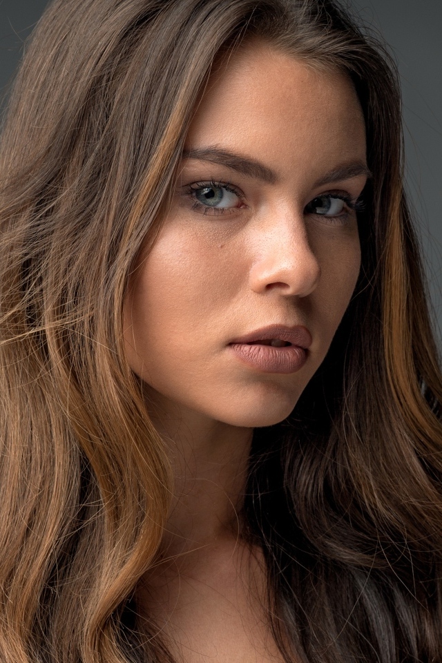 Красивая девушка шатенка на сером фоне 