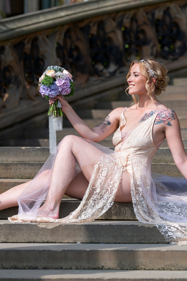 Красивая девушка невеста в платье с букетом на ступеньках