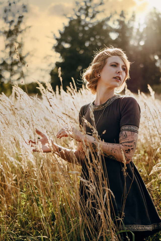 Красивая девушка в черном платье на поле с колосьями