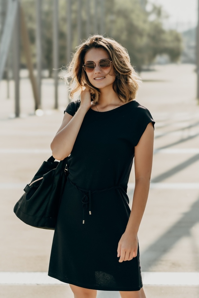 Красивая девушка в черном платье в очках