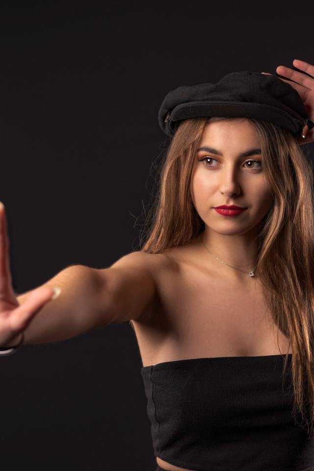 Красивая девушка в кепке на черном фоне