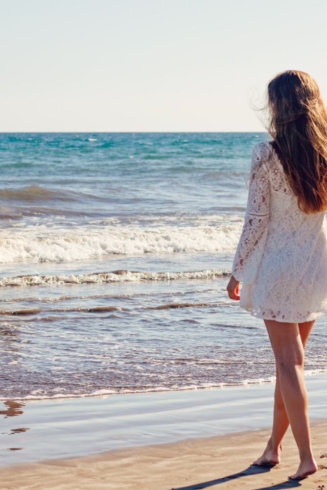 Красивая девушка в коротком белом платье на берегу моря