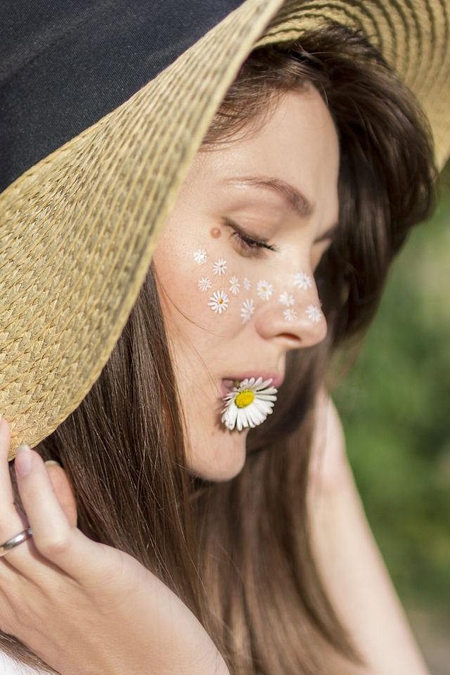 Красивая девушка в соломенной шляпе с ромашкой