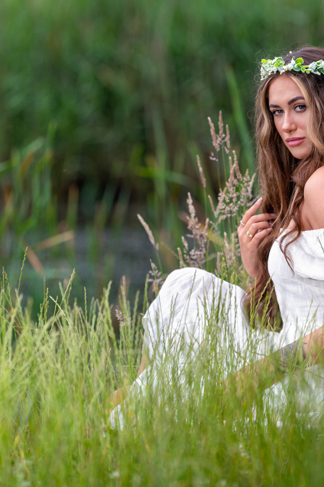 Красивая девушка в белом платье с венком на голове у пруда 