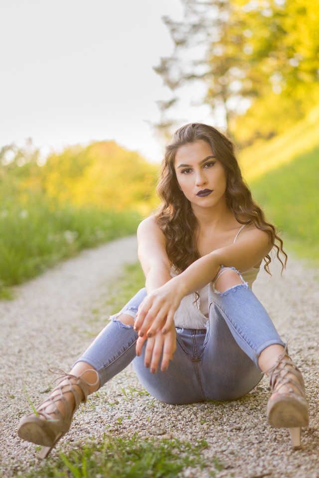 Красивая девушка сидит на дороге летом