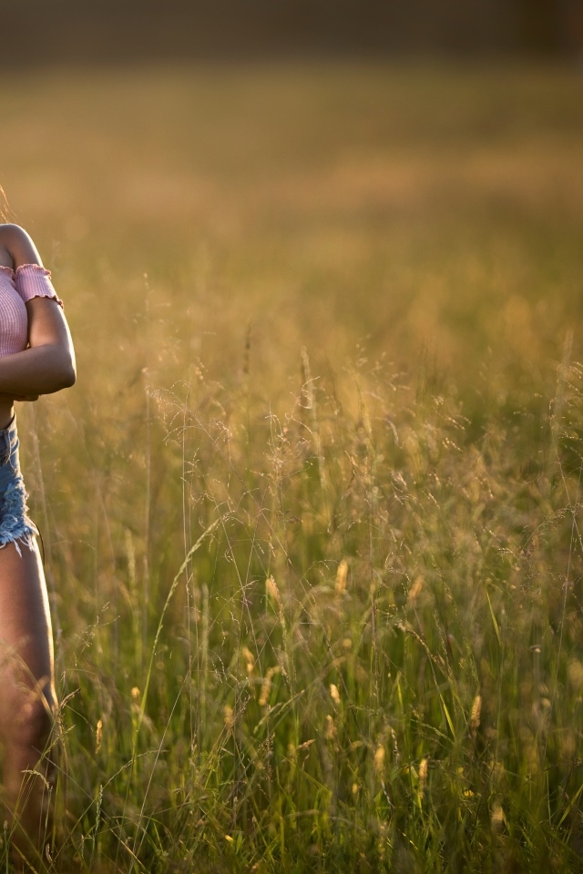 Красивая девушка стоит на поле в траве