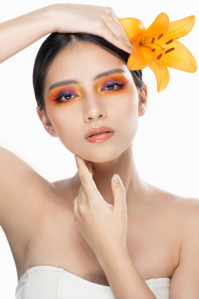 Красивая девушка с цветком лилии в волосах на белом фоне