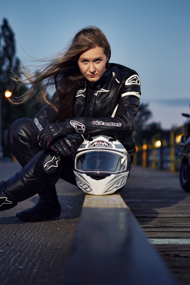 Красивая девушка с мотоциклом сидит на дороге