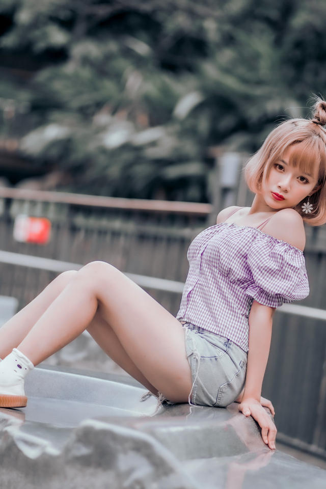 Милая девушка азиатка сидит на камне