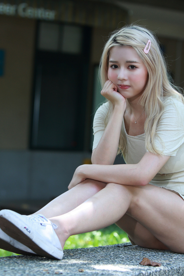 Милая азиатка сидит на холодном бетоне