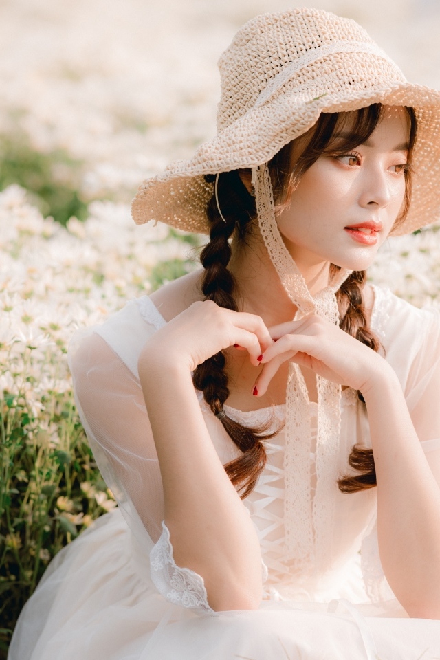 Милая азиатка в шляпе и белом платье 