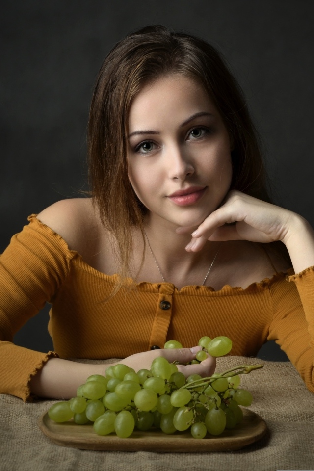 Милая шатенка ест белый виноград