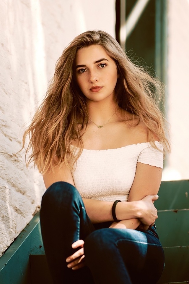 Милая девушка брюнетка сидит на ступеньках